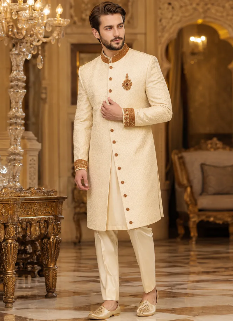 Full-length cream sherwani for groom with gold detailing and embellished buttons