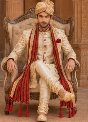 Ivory groom sherwani with gold embroidery, deep red shawl and matching turban