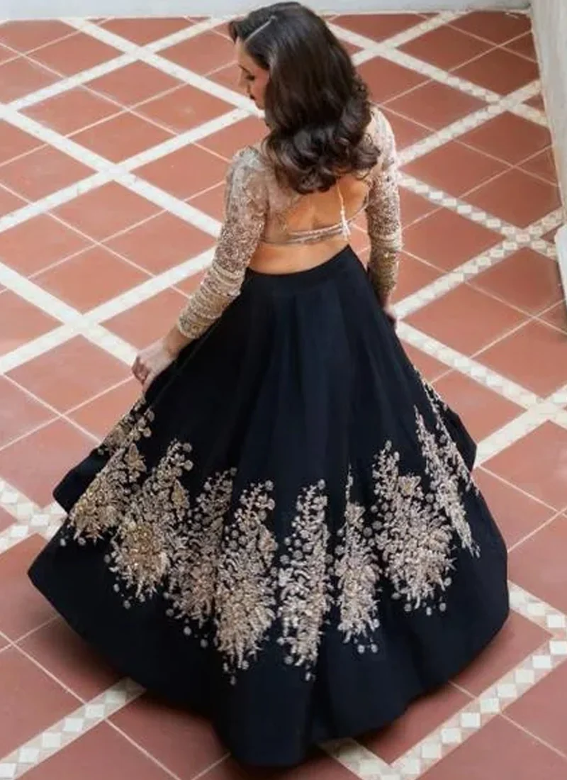 Black bridal lehenga choli front view with gold blouse and oversized floral embroidery on the flared skirt