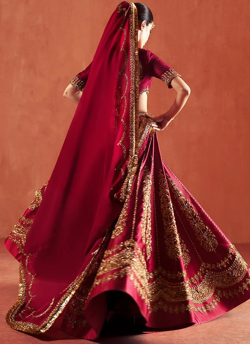 Deep red Baraat lehenga choli in a flowing front view with large gold floral motifs and scalloped embroidered borders.