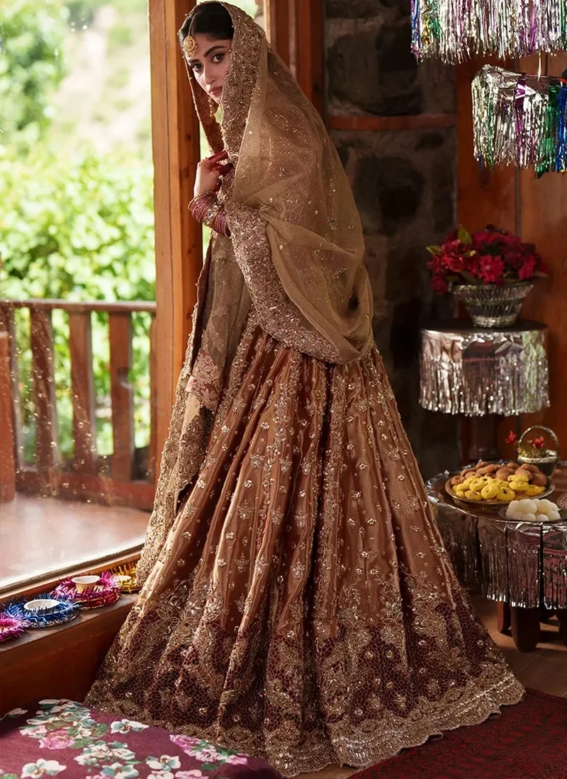 Three-quarter rear-side view of the flared lehenga with long folds, scattered gold sprigs and a scalloped floral hem beneath the champagne veil