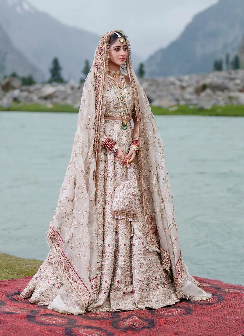 ivory-baraat-lehenga-choli-with-kiran-lace-dupatta-borders-01 Full-length standing view of the ivory Baraat lehenga choli: cropped embellished choli, wide embroidered ghera and sheer dupatta with maroon kiran-lace borders