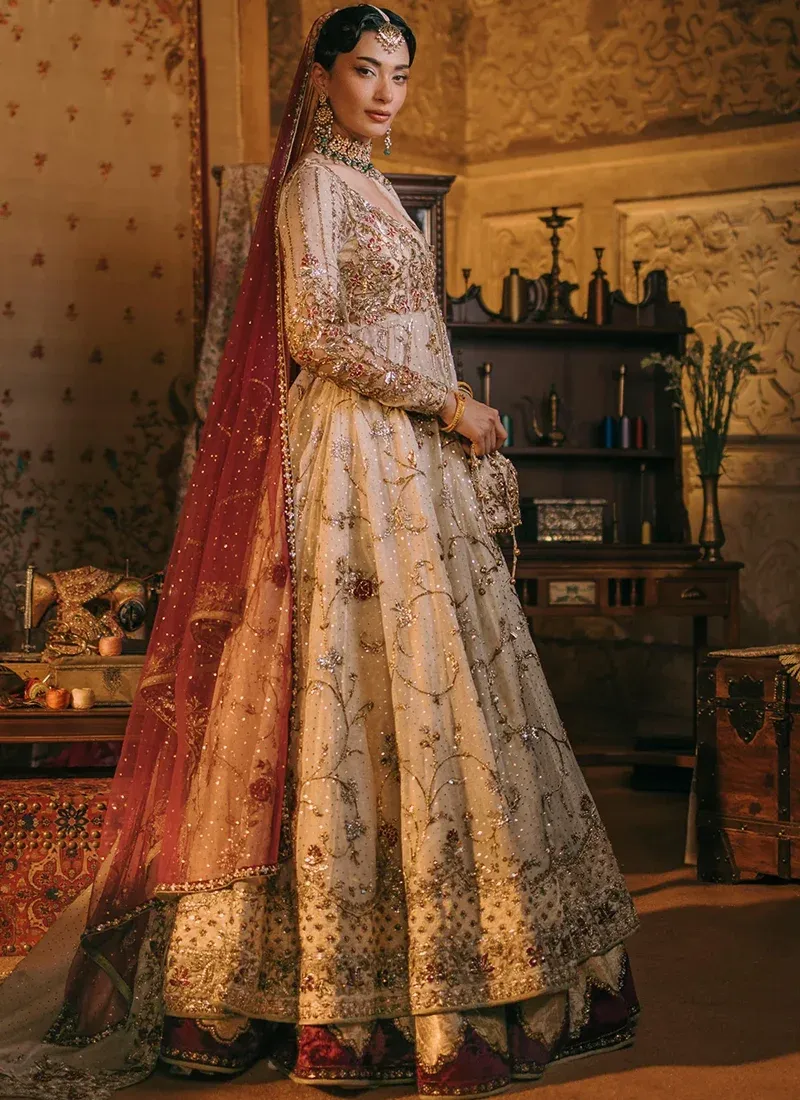 Ivory gown bodice close-up showing a scooped neckline and gold floral embroidery across sheer full sleeves
