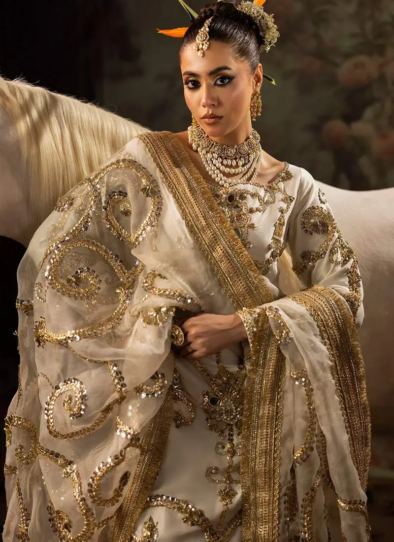 Ivory formal shalwar suit front view with gold scrollwork, embellished shalwar hems and wide bordered dupatta