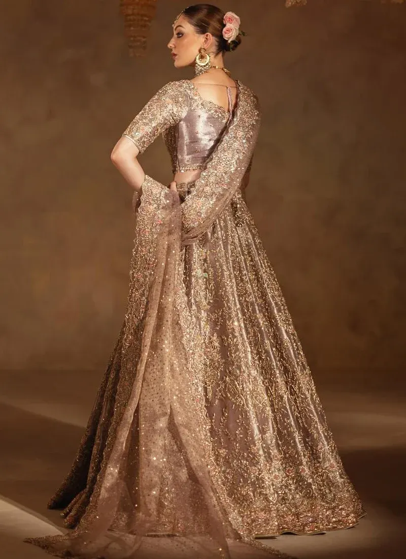 Smoky lilac bridal lehenga choli in side view with sweeping gold floral embroidery and a sheer dupatta