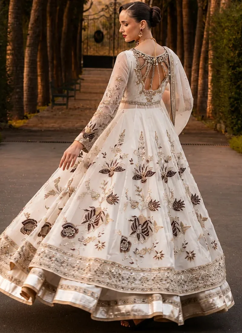 White bridal pishwas front view with black floral motifs and an ornate gold hem over a lehenga