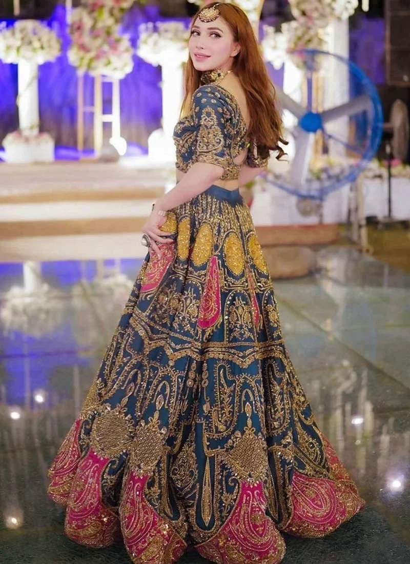Zinc blue lehenga choli from the back with ornate gold embroidery and fuchsia paisley hem motifs